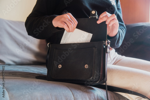 Detalle de una mujer sacando una compresa menstrual de su bolso negro photo