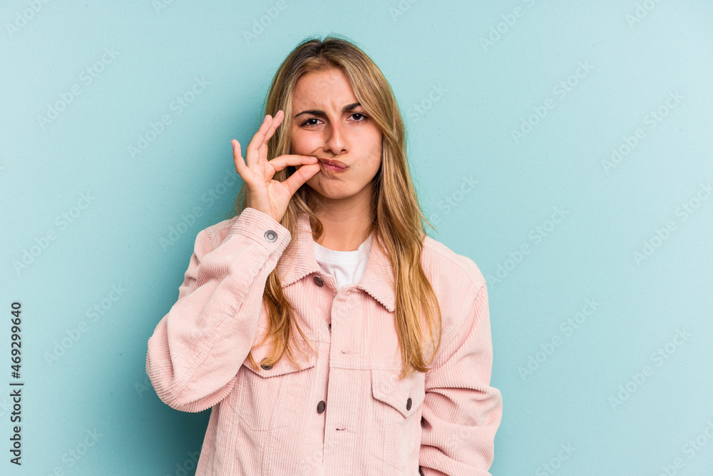 Young caucasian blonde woman isolated on blue background with fingers on lips keeping a secret. Young caucasian blonde woman isolated on blue background with fingers on lips keeping a secret.