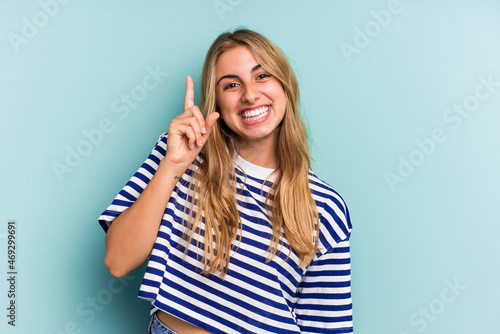 Young caucasian blonde woman isolated on blue background  showing number one with finger.