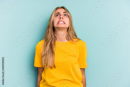 Young caucasian blonde woman isolated on blue background shouting very angry, rage concept, frustrated.