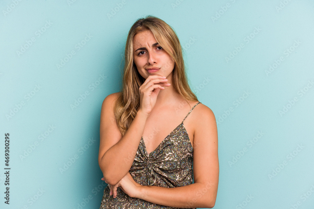 Young caucasian blonde woman isolated on blue background thinking and looking up, being reflective, contemplating, having a fantasy. Young caucasian blonde woman isolated on blue background thinking and looking up, being reflective, contemplating, having a fantasy.