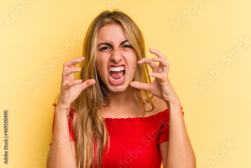 Young caucasian blonde woman isolated on yellow background  screaming with rage.