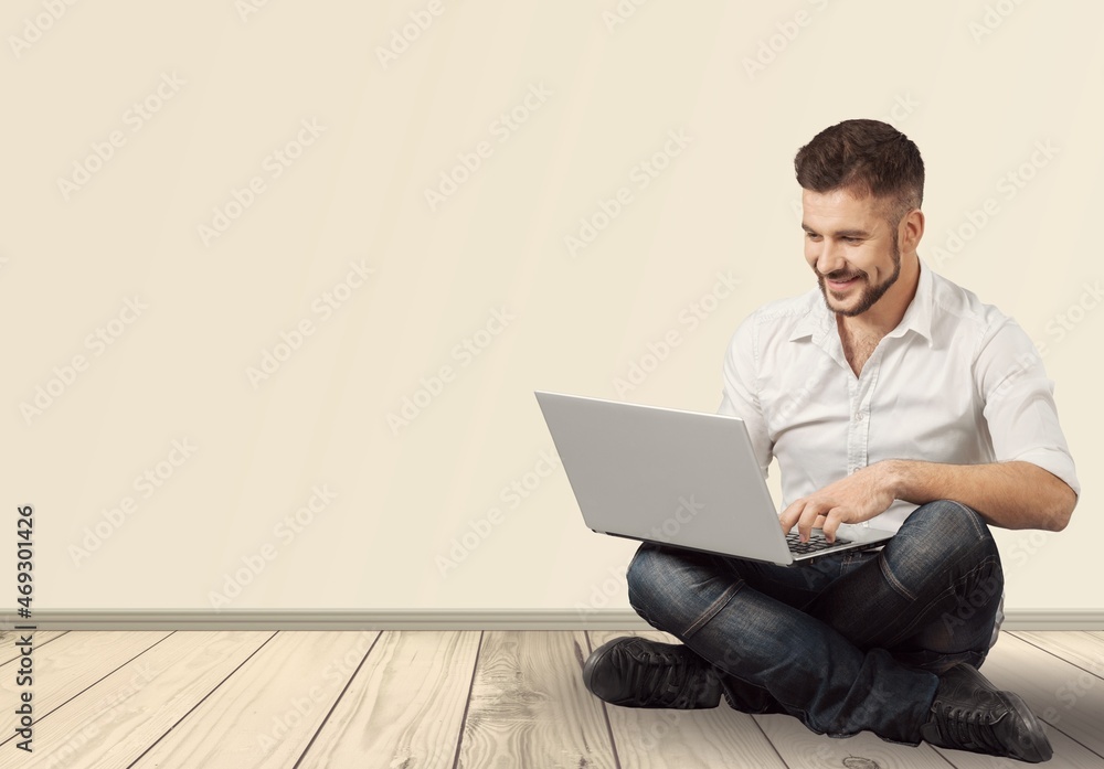 Portrait of young modern businessman holding laptop and looking at camera