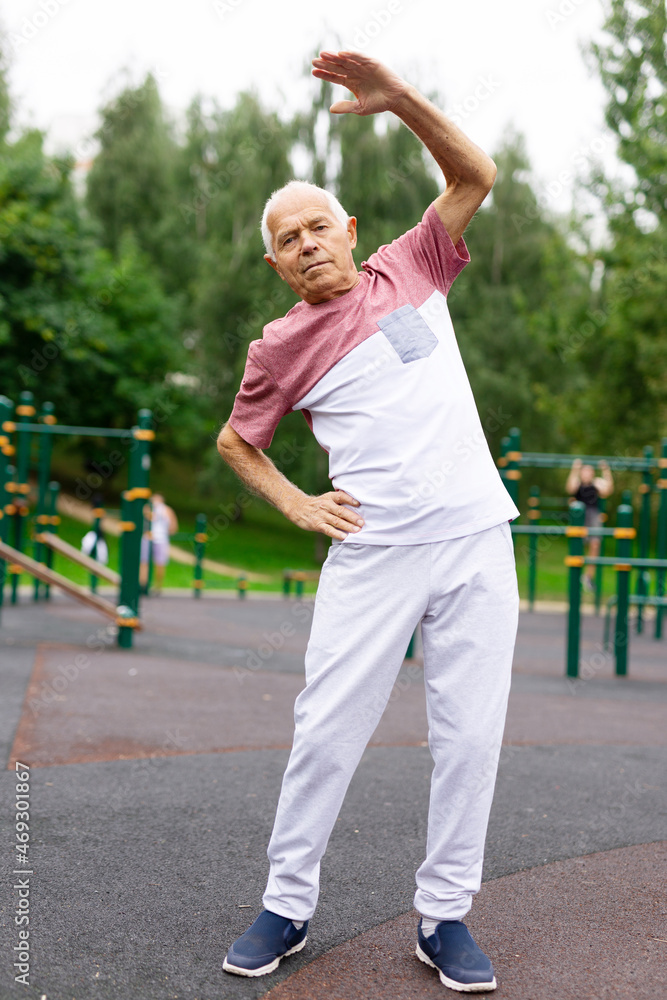 Elderly man doing fitness exercises outdoors