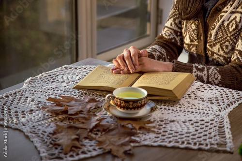 Person sitting drinking tea and reading or writing a book in a calm and cozy environment. Concept of leisure time and relaxation.