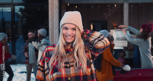 Excited beautiful happy young blonde woman in winter hat smiling at camera at fun Christmas friends party slow motion.