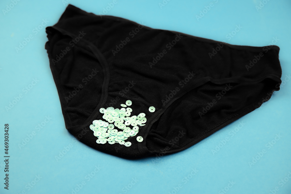 Concept of abnormal green vaginal discharge, signs of STD like trich. Black  panties with green glitter. Stock Photo