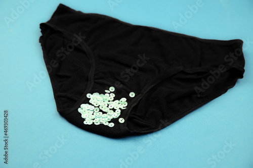 Concept of abnormal green vaginal discharge, signs of STD like trich. Black panties with green glitter. photo