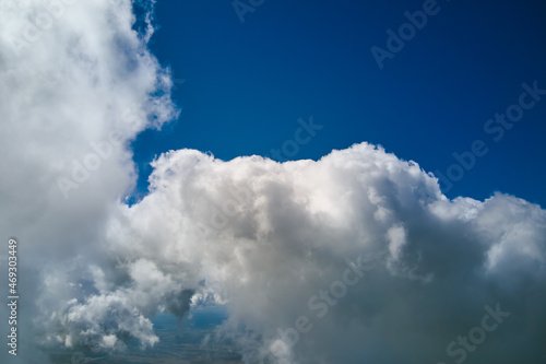 Aerial view from airplane window at high altitude of earth covered with white puffy cumulus clouds