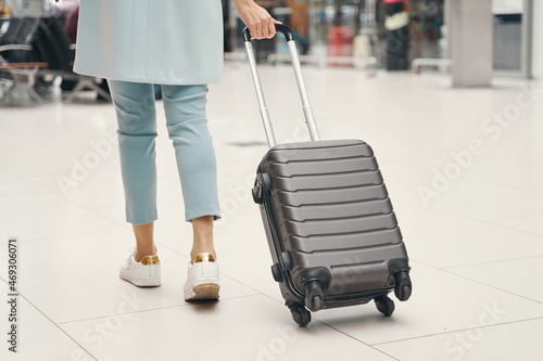 Air traveler wheeling baggage through airport terminal