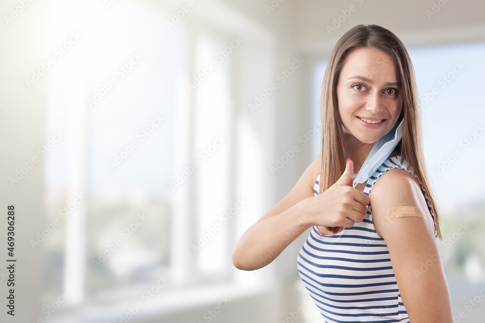 Happy adult woman shows her arm that just received the Covid-19 vaccine in the new normal