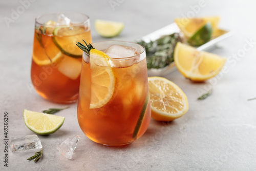 Iced tea with lemon, lime and ice garnished with rosemary twigs.