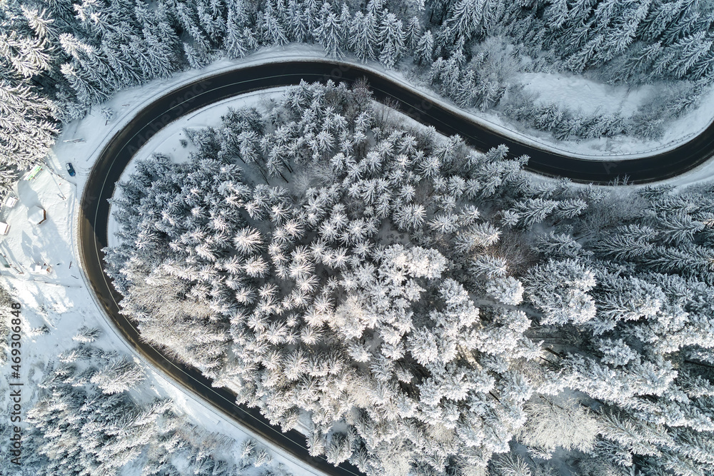 Aerial view of winter landscape with snow covered mountain woods and winding forest slippery road Aerial view of winter landscape with snow covered mountain woods and winding forest slippery road