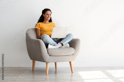 Free Download Remote Work. Smiling Female Using Laptop While Sitting In Armchair At Home - GFXLoad