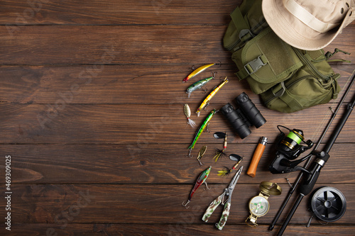 Fishing tackle - fishing spinning rod, hooks and lures on wooden background. Active hobby recreation concept.