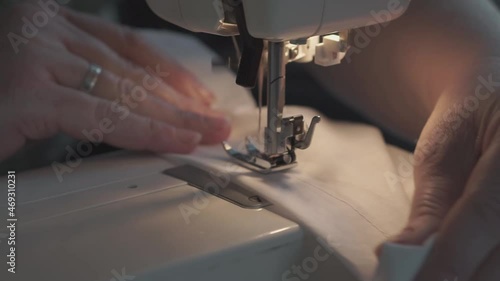 Female hands with denim on the sewing machine, close-up. The concept of clothing repair, recycling, home hobbies and work at home.