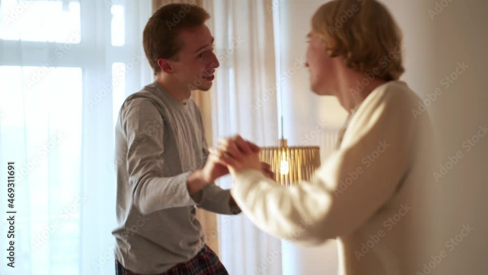 Cheerful gay couple dancing on the bed Cheerful gay couple dancing on the bed