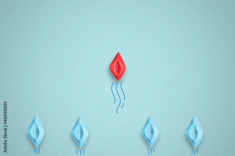Fototapeta premium Red paper boat in front of line from blue ships in sea for leadership concept.