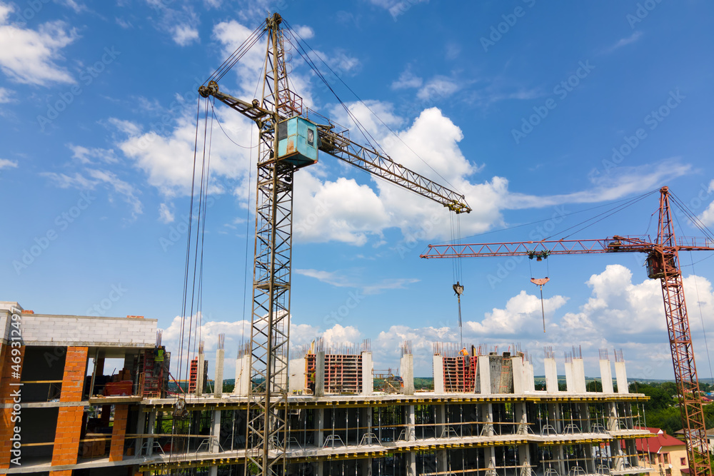 Tower crane at high concrete residential building under construction. Real estate development concept