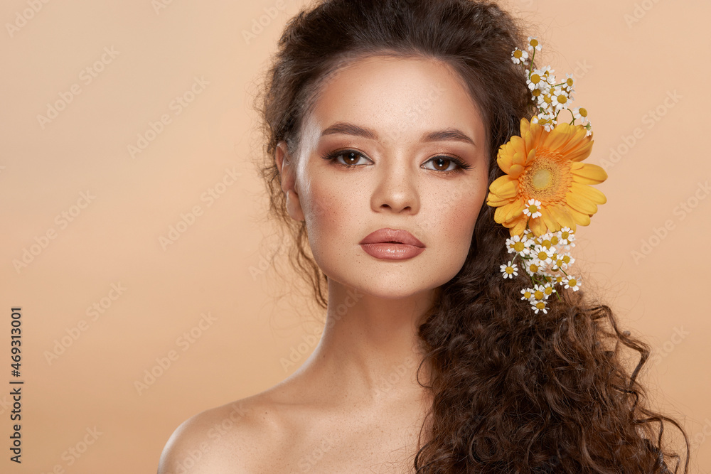 Elegant woman with flowers in curly hair. Pretty girl with perfect make-up. Close-up studio beauty face portrait. Young beautiful fashion model looking at you