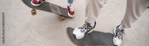 partial view of men in sneakers riding skateboards outdoors, banner.