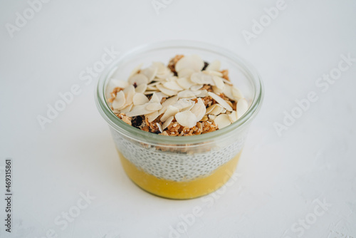 Mango chia pudding with granola and almond flakes on white table photo