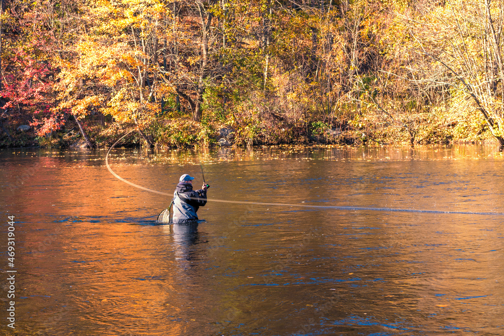 A photograph of a fly fisherman in the river casting his line