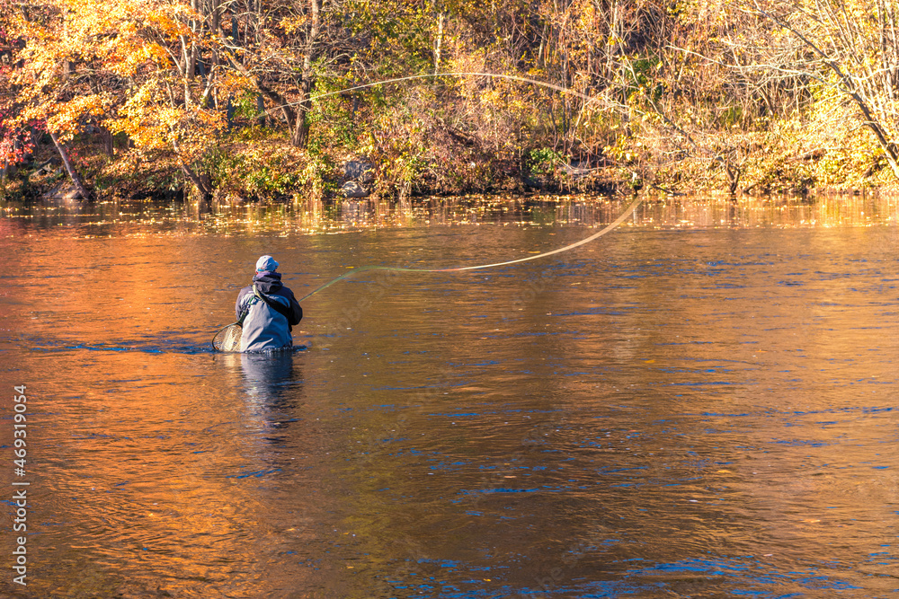 A photograph of a fly fisherman in the river casting his line