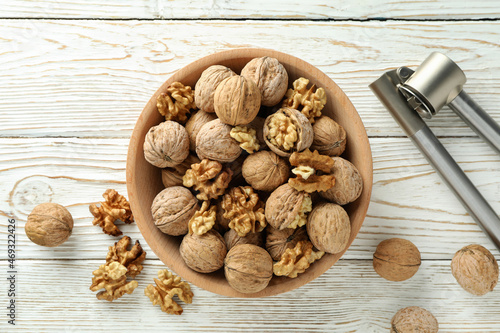 Nutcracker and bowl of walnuts on white wooden background photo