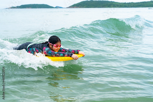 Canvas Print cute asian girl wearing a black swimsuit running on the waveboard surf in the se