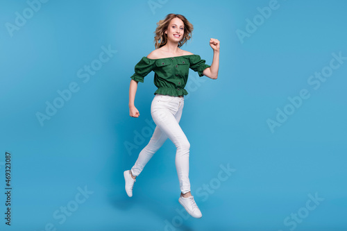 Fototapeta Naklejka Na Ścianę i Meble -  Photo of charming sporty lady jump run wear bear shoulders green blouse pants shoes isolated blue color background