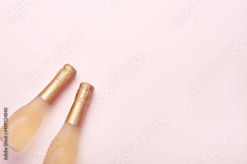 Champagne bottle, gift or present box and golden shiny sparkle star confetti on pink background. Christmas or New Year composition or card. Celebration flat lay. Party creative concept. Top view.