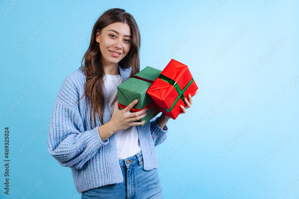 Excited young beautiful girl holding gift boxes isolated on blue studio background. Concept of emotions, Merry Christmas Excited young beautiful girl holding gift boxes isolated on blue studio background. Concept of emotions, Merry Christmas