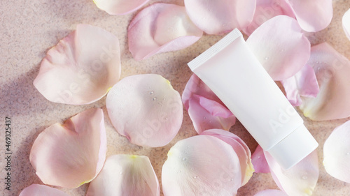 Cosmetic tube with face or body cream on a light background with rose petals. Anti aging care concept