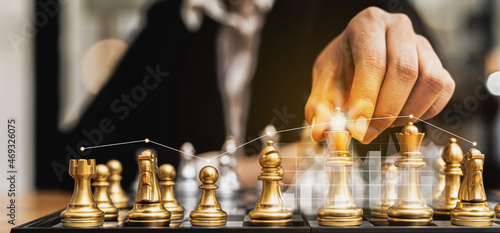 Person holding golden chess pieces to run a game, conceptual image of businessman playing chessboard compared to managing a business on risk, chart graphics showing financial flows.