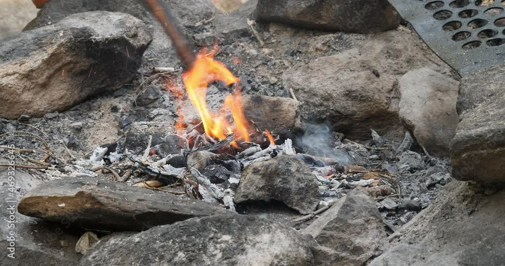 Preparation of the camp hearth for baking. Fire keen on designated areas outdoor. Campfire. Digging and arranging coals in the hearth with a stick. Preparation of the camp hearth for baking. Fire keen on designated areas outdoor. Campfire. Digging and arranging coals in the hearth with a stick.