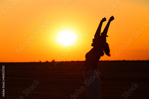 Profile of excited woman raising arms at sunset