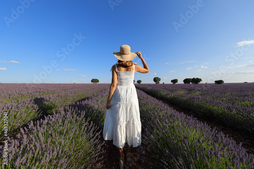 Woman walking holding hat in a lavender field