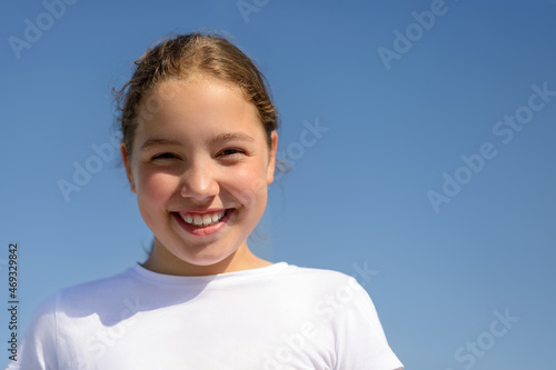 Happy smiling teenage girl in white t-shirt on blue background.