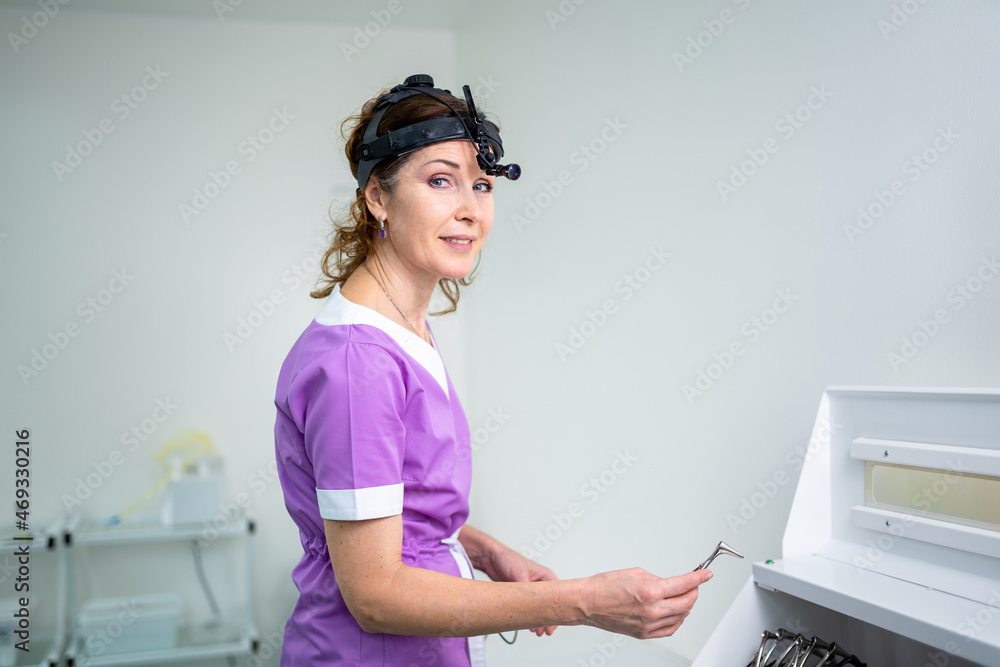 Profession medical industry. Portrait of woman ENT doctor posing in office before examining patient. Physician in bright colored uniform with medical equipment and tools for ENT practice in hospital Profession medical industry. Portrait of woman ENT doctor posing in office before examining patient. Physician in bright colored uniform with medical equipment and tools for ENT practice in hospital