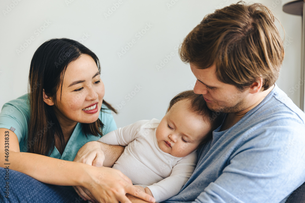 Young Parents Looking At Sleeping Daughter