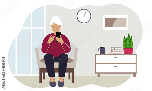 Happy grandmother is busy with a mobile phone sitting in a chair in the living room. Relax and work at home.