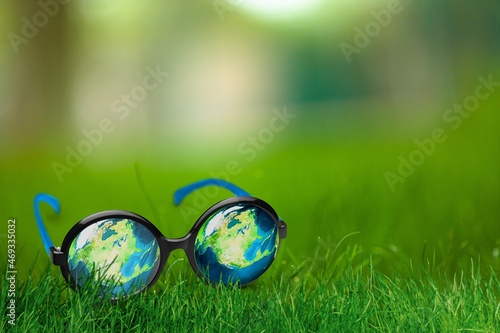 Looking for a Better Environmental World concept, eyeglasses with Earth reflection on green grass