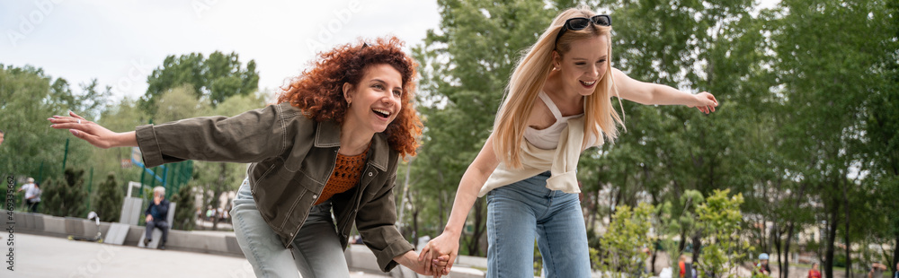 young excited skaters holding hands while having fun in park, banner. young excited skaters holding hands while having fun in park, banner.