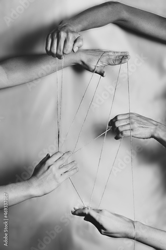 Several hands joined with a thin rope making various connections between people. Union, diversity, community, sisterhood.
