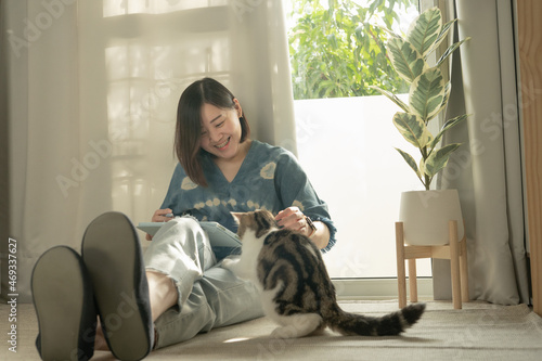 asian woman smile and happy during play with her cat and use tablet meeting and working from home