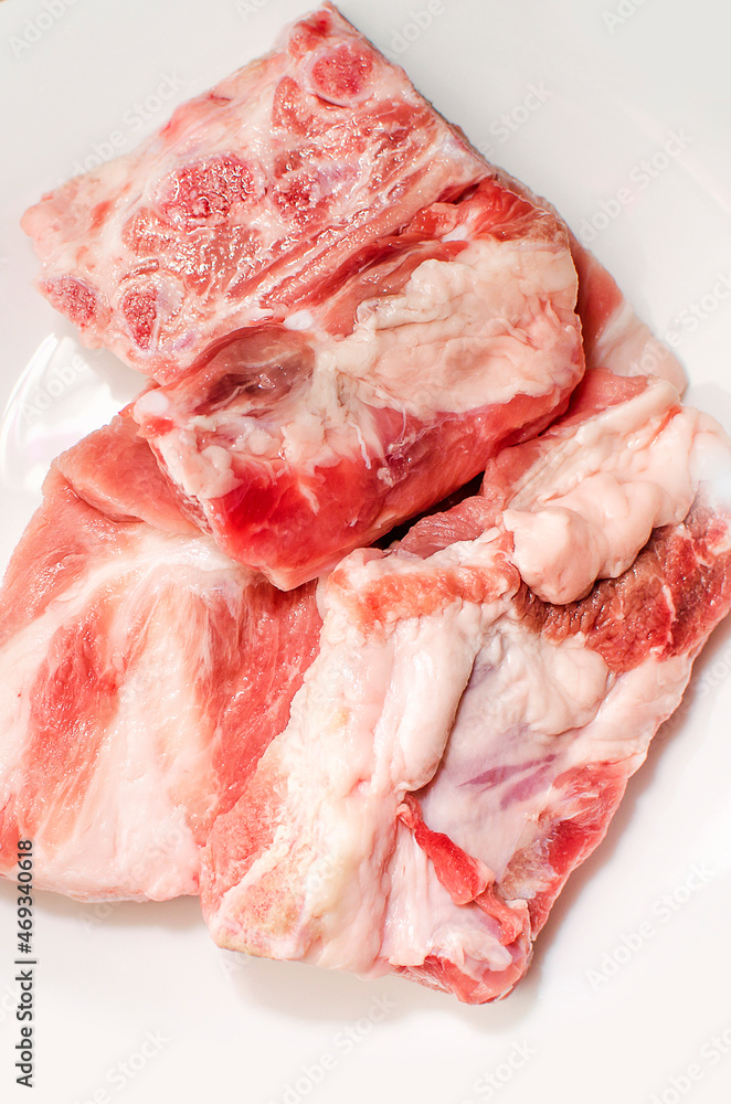 Pork ribs for making soup on a white plate, close-up. Pork ribs for making soup on a white plate, close-up.