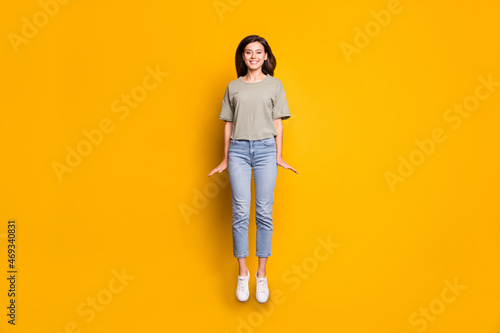 Full length body size view of pretty funny cheerful skinny girl jumping having fun isolated over bright yellow color background
