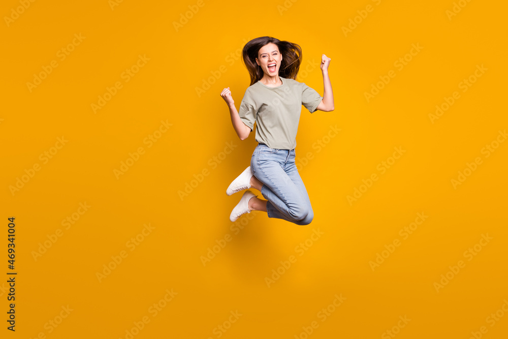 Full length photo of crazy happy woman jump air up raise fists celebrate win isolated on yellow color background