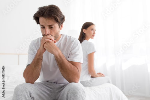 Cuadro en lienzo Sad upset offended millennial caucasian man sitting on bed, ignoring woman in be